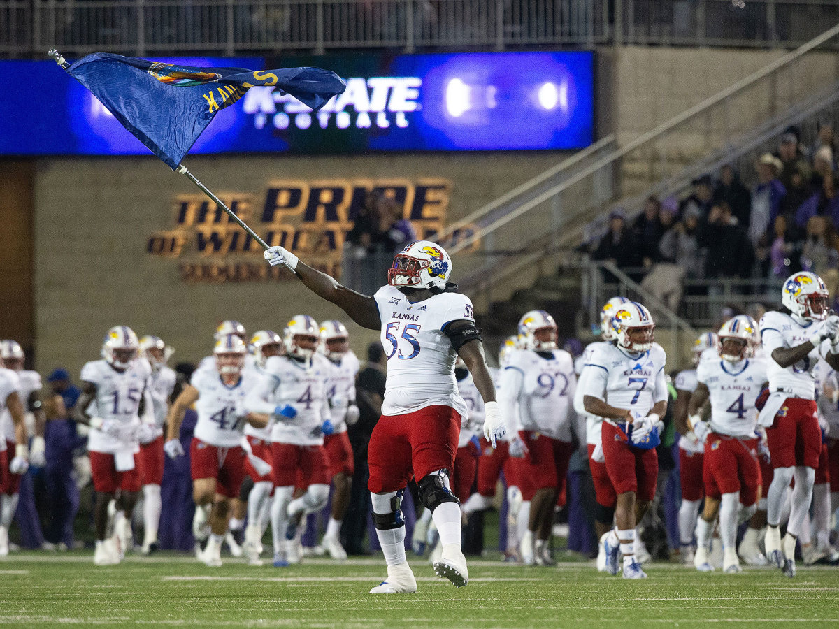 A Kansas football player waves a Jayhawks flag